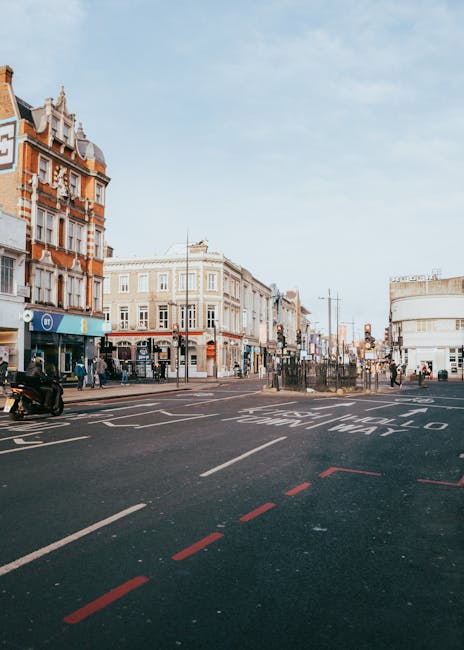Image of a busy street scene on High Road Finchley during daytime, featuring a mix of Victorian and modern architecture. The street is paved with asphalt, showing painted road markings and a designated bus lane. A few pedestrians are walking along the sidewalks, which are lined with shops, cafes, and storefronts. The sky is partly cloudy with natural daylight illuminating the scene, reflecting a typical urban environment. The image emphasizes the vibrant, well-maintained appearance of the area, aligning with the context of residential and commercial surroundings related to high street cleaning and maintenance, as discussed on finchleycarpetcleaning.org.uk under the page about high road Finchley end of tenancy cleaning advice, although the image itself depicts an exterior street scene rather than indoor cleaning.